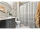 Well-lit bathroom with a round mirror, neutral color scheme, and a combination shower and bathtub at 1212 Magpie Ave, Brighton, CO 80601