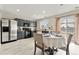 Elegant dining room with a table set for a meal, complemented by modern appliances and stylish gray cabinetry at 1212 Magpie Ave, Brighton, CO 80601