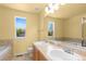 Bright bathroom featuring dual sinks, a tub, and a window with a view at 6760 E 129Th Ave, Thornton, CO 80602