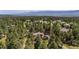 Aerial view of a home surrounded by green pine trees, with city views and mountain range visible in the distance at 465 Indian Way, Monument, CO 80132