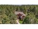 Two-story red brick home nestled among mature trees with a stone walkway leading to the entrance at 465 Indian Way, Monument, CO 80132