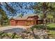 View of the rear exterior showcasing a large garage, stone feature, and lush greenery at 465 Indian Way, Monument, CO 80132