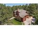 Two-story home with an attached two-car garage and covered deck, all surrounded by lush green trees at 465 Indian Way, Monument, CO 80132