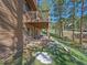 Backyard patio and yard featuring mature trees and partially snow-covered lawn at 4228 Scenic Village Dr, Evergreen, CO 80439