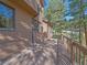 Exterior view of a home featuring a large wooden deck with a view of surrounding mature trees at 4228 Scenic Village Dr, Evergreen, CO 80439