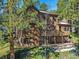 Inviting two-story home featuring a wood exterior, a deck, a walkout basement, and mature trees at 4228 Scenic Village Dr, Evergreen, CO 80439