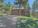Inviting home boasts a two-car garage, covered entry, and is nestled amidst a lush, green lawn and mature trees at 4228 Scenic Village Dr, Evergreen, CO 80439