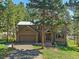 Charming home featuring a two-car garage and a welcoming covered front entry in a wooded, landscaped setting at 4228 Scenic Village Dr, Evergreen, CO 80439