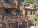 Exterior of a multi-story home featuring a deck, wood siding, and mature trees at 4228 Scenic Village Dr, Evergreen, CO 80439
