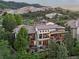 Stone home featuring a large outdoor patio, balcony, and views of the surrounding mountain landscape at 7208 Raphael Ln, Littleton, CO 80125