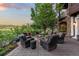 Backyard patio with outdoor seating surrounding a fireplace, large tree, and landscaped yard at 7208 Raphael Ln, Littleton, CO 80125