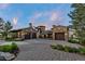 Stone home featuring a three-car garage and a circular entryway, complemented by manicured landscaping and a paved driveway at 7208 Raphael Ln, Littleton, CO 80125