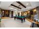 Recreation room features stone accents, wooden beams, pool table, and a bar for entertaining at 7208 Raphael Ln, Littleton, CO 80125