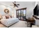 Bright main bedroom with plush bedding, wooden desk, ceiling fan, and glass doors to outside at 7208 Raphael Ln, Littleton, CO 80125