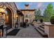 Outdoor sitting area featuring a stone fireplace and seating, complemented by potted plants and lush greenery at 7208 Raphael Ln, Littleton, CO 80125