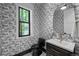 Stylish powder room with patterned wallpaper, a black toilet, and a decorative mirror at 451 S Franklin St, Denver, CO 80209