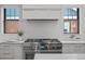 Close up of a modern kitchen featuring a professional gas range, white cabinets and tiled backsplash at 451 S Franklin St, Denver, CO 80209