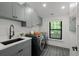 Well-equipped laundry room with modern washer and dryer, sink and gray cabinets enhancing functionality and style at 451 S Franklin St, Denver, CO 80209