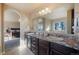 A bright bathroom boasts a double vanity, natural light, and an arched doorway to the Primary bedroom at 19703 Serenity Springs Pt, Monument, CO 80132