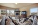 Comfortable living room features a stone fireplace, neutral carpet, large windows, and a mounted television at 19703 Serenity Springs Pt, Monument, CO 80132