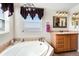 Relaxing bathroom features a soaking tub, wood vanity and modern light fixture at 5129 S Tom Bay Rd, Bennett, CO 80102