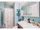 Bathroom featuring blue walls, shower with floral curtain, storage shelves, and vanity with modern faucet at 3937 W Grand Ave, Littleton, CO 80123