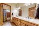 Bathroom with double sinks, light wood cabinets, large mirror, and tiled floor at 4456 Mohawk Dr, Larkspur, CO 80118
