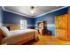 Bedroom with blue walls, hardwood floors, natural light, and a ceiling fan at 4456 Mohawk Dr, Larkspur, CO 80118