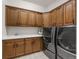 Functional laundry room with wood cabinets, counter space, sink, and stainless steel washer and dryer at 5625 Heritage Oak Dr, Parker, CO 80134