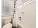 White bathroom with a soaking tub, a shower with leaf-patterned curtains, and a window at 14437 Grape St, Thornton, CO 80602