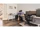 Well-lit home office with a spacious desk, ergonomic chair, and dark, modern flooring at 14437 Grape St, Thornton, CO 80602