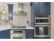 Close up of kitchen featuring stainless steel appliances, a herringbone backsplash, and blue cabinets at 6248 S Coventry Ln, Littleton, CO 80123