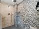 Luxurious shower featuring pebble stone walls, multiple showerheads, and built-in shelving at 6248 S Coventry Ln, Littleton, CO 80123