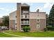 Multi-story condo with balconies, stone chimney, neutral siding, and well-maintained lawn at 4896 S Dudley St # 8-11, Littleton, CO 80123