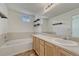 Bathroom featuring double sinks, a large mirror, shelving, and a soaking tub at 16051 E Geddes Dr # 66, Aurora, CO 80016