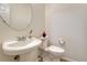 Charming powder room with a pedestal sink, round mirror, and a toilet at 16051 E Geddes Dr # 66, Aurora, CO 80016
