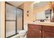 Well-lit bathroom featuring a tiled shower with glass doors, vanity with storage, and neutral paint at 15056 Fillmore Way, Thornton, CO 80602