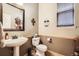 Charming powder room features a pedestal sink, decorative mirror, and a neutral color palette at 15056 Fillmore Way, Thornton, CO 80602