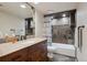 Bathroom with granite countertops, dark wood cabinets, and a shower-tub combo with stylish tile at 3305 White Oak Ln, Highlands Ranch, CO 80129