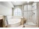 Bright bathroom features a soaking tub under an arch window and glass-enclosed shower with a built-in seat at 3305 White Oak Ln, Highlands Ranch, CO 80129