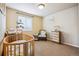 Cozy bedroom with natural light, featuring a round crib, changing table, chair, and chest of drawers at 3305 White Oak Ln, Highlands Ranch, CO 80129