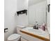 Cozy half-bathroom with a pedestal sink, white toilet, wood trim, and decorative shelf at 5282 Devon Ave, Castle Rock, CO 80104