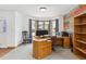 Well-lit home office with a bay window, carpeted floor, custom wood accent wall, and traditional wood furniture at 5282 Devon Ave, Castle Rock, CO 80104