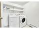 Bright laundry room featuring a white washer and dryer and built-in shelves at 12341 E Cedar Cir, Aurora, CO 80012
