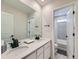 Bright bathroom featuring a double sink vanity, stone countertop, and a view to a tiled shower and toilet at 14687 Eudora St, Thornton, CO 80602