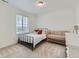 Simple bedroom with a black metal bed, crib and light colored carpet illuminated by a large window at 14687 Eudora St, Thornton, CO 80602