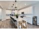 Bright kitchen featuring white cabinets, stainless steel appliances, large island with pendant lighting and wood-look floors at 14687 Eudora St, Thornton, CO 80602
