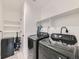 Modern laundry room with front loading washer/dryer units, shelving, and vinyl flooring at 14687 Eudora St, Thornton, CO 80602