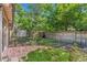 Charming backyard with mature trees, brick patio, garden beds, and wooden fence providing a serene outdoor space at 2518 S Patton Ct, Denver, CO 80219