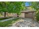 Inviting exterior featuring a charming brick facade, lush lawn, mature trees, and a convenient attached two car garage at 2518 S Patton Ct, Denver, CO 80219